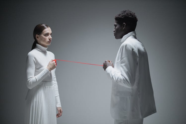 Man And Woman In White Clothes Holding A Red String