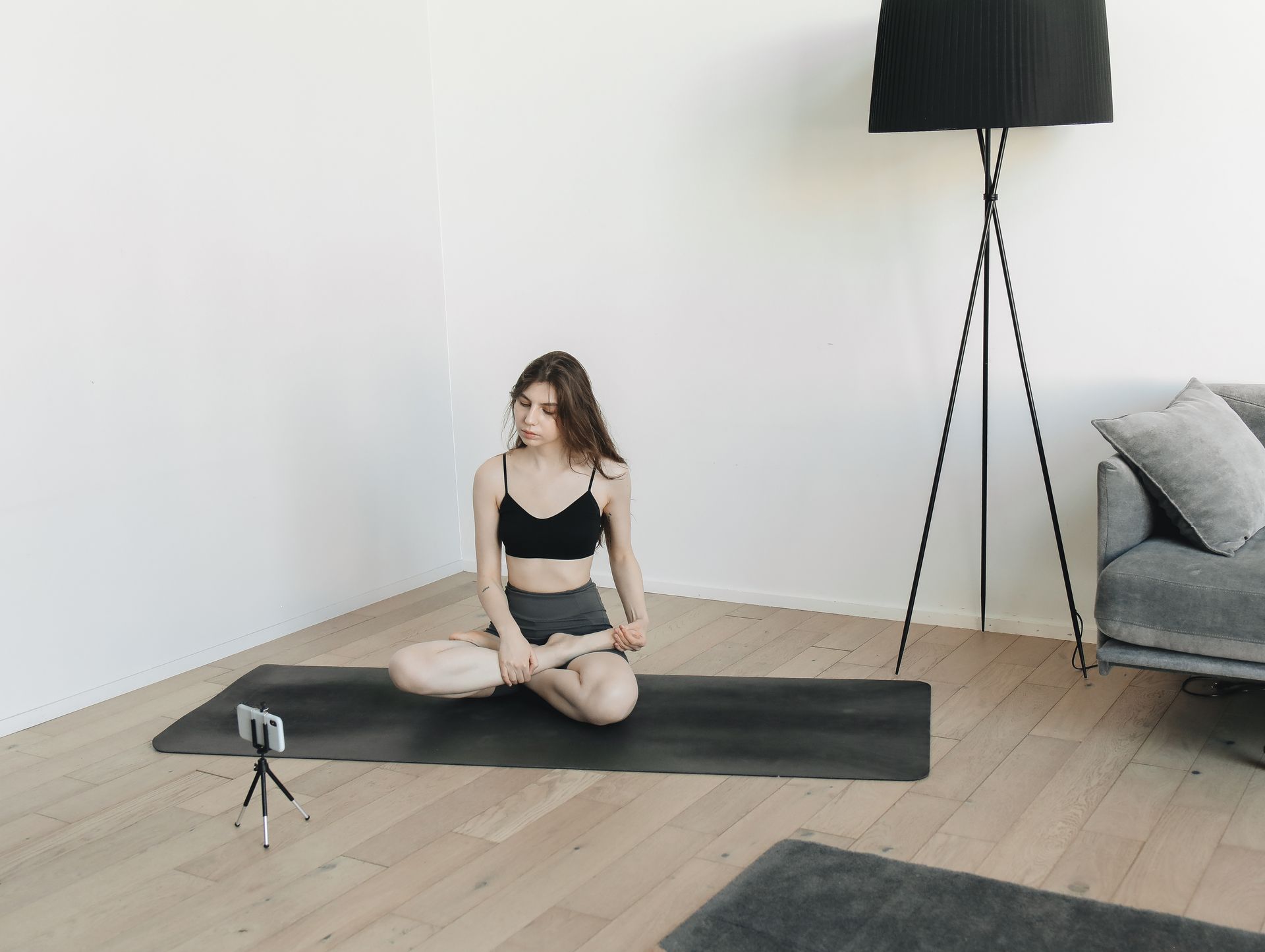 A woman practicing a yoga pose indoors with a smartphone for online vlogging.