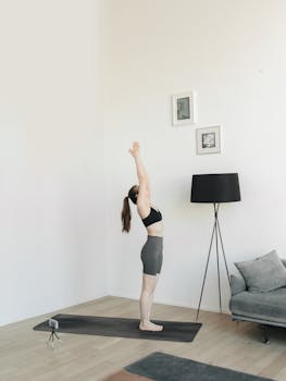 An adult woman performs a yoga pose on a mat indoors, captured with Canon EOS camera.