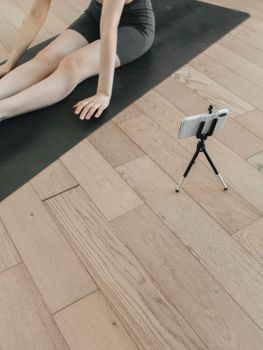 Woman using a smartphone for yoga practice at home on a yoga mat. Perfect for exercise and fitness concepts.