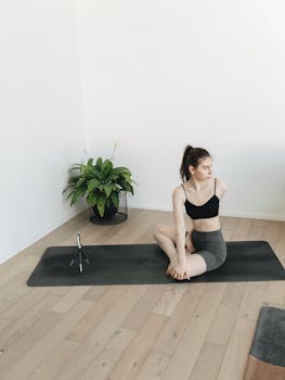 A young woman practicing yoga in a bright indoor setting with a mat and a plant for ambiance.