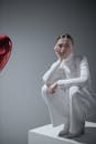 时尚的女人在白色的衣服摆姿势与心脏气球在简约的工作室设置