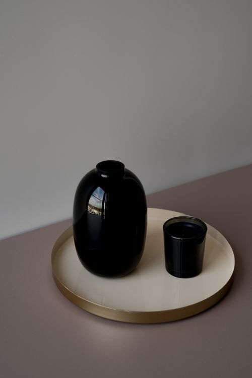 Free A minimalist photo of a black vase and cup on a decorative tray with soft lighting. Stock Photo