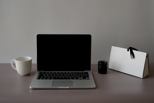 A sleek, minimalist workspace featuring a laptop, ceramic cup, and a stylish paper bag. Perfect for productivity.