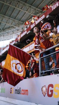 Fans engaging passionately with flags and team spirit during a soccer match at a lively stadium atmosphere.