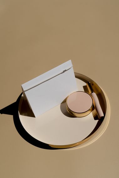 Compact and card on a brass tray, by alleksana on Pexels