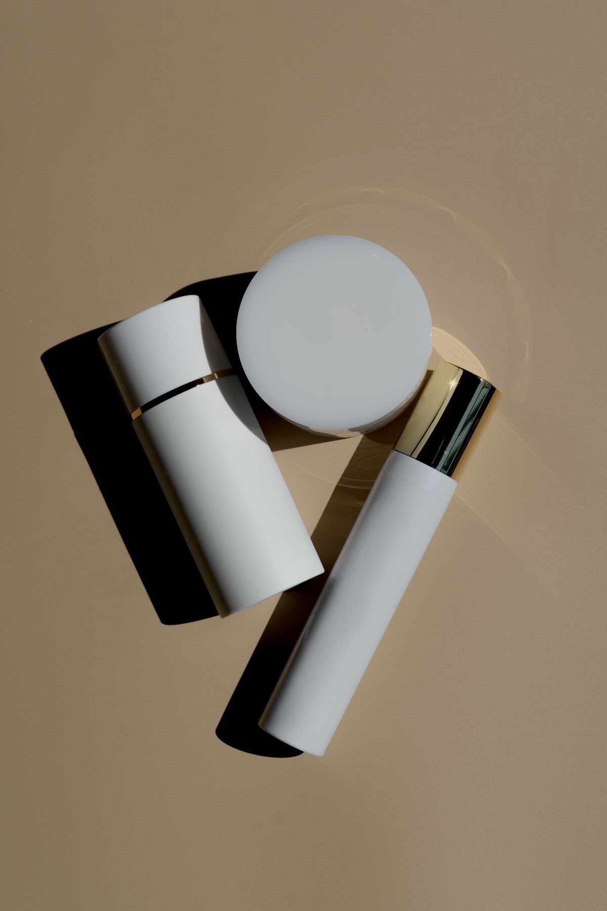 Minimal skincare tubes and moisturizer jar arranged on a beige background