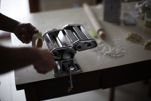 Free Close-up of a person using a hand crank pasta maker in a kitchen setting. Stock Photo