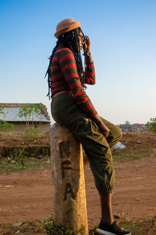 Free African woman sitting on a post in Kampala, Uganda, enjoying a sunny day. Stock Photo