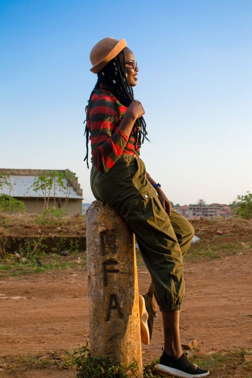 Free Smiling African woman with dreadlocks sitting outdoors in Kampala, Uganda. Stock Photo