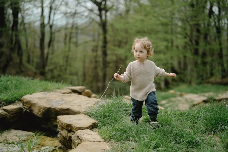 A Child Running While Holding A Stick