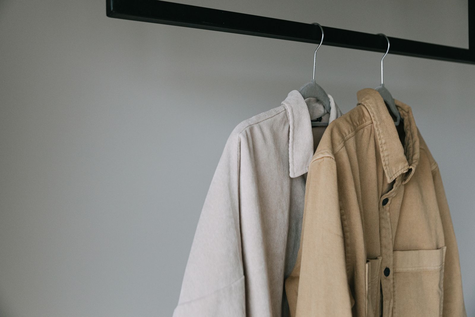 Close-up of beige shirts hanging on a clothing rack.
