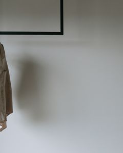 A beige blazer hangs on a minimalist metal rack, providing a serene and stylish wardrobe aesthetic.