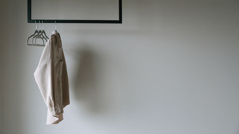 A beige blazer hangs on a minimalist metal rack, providing a serene and stylish wardrobe aesthetic.