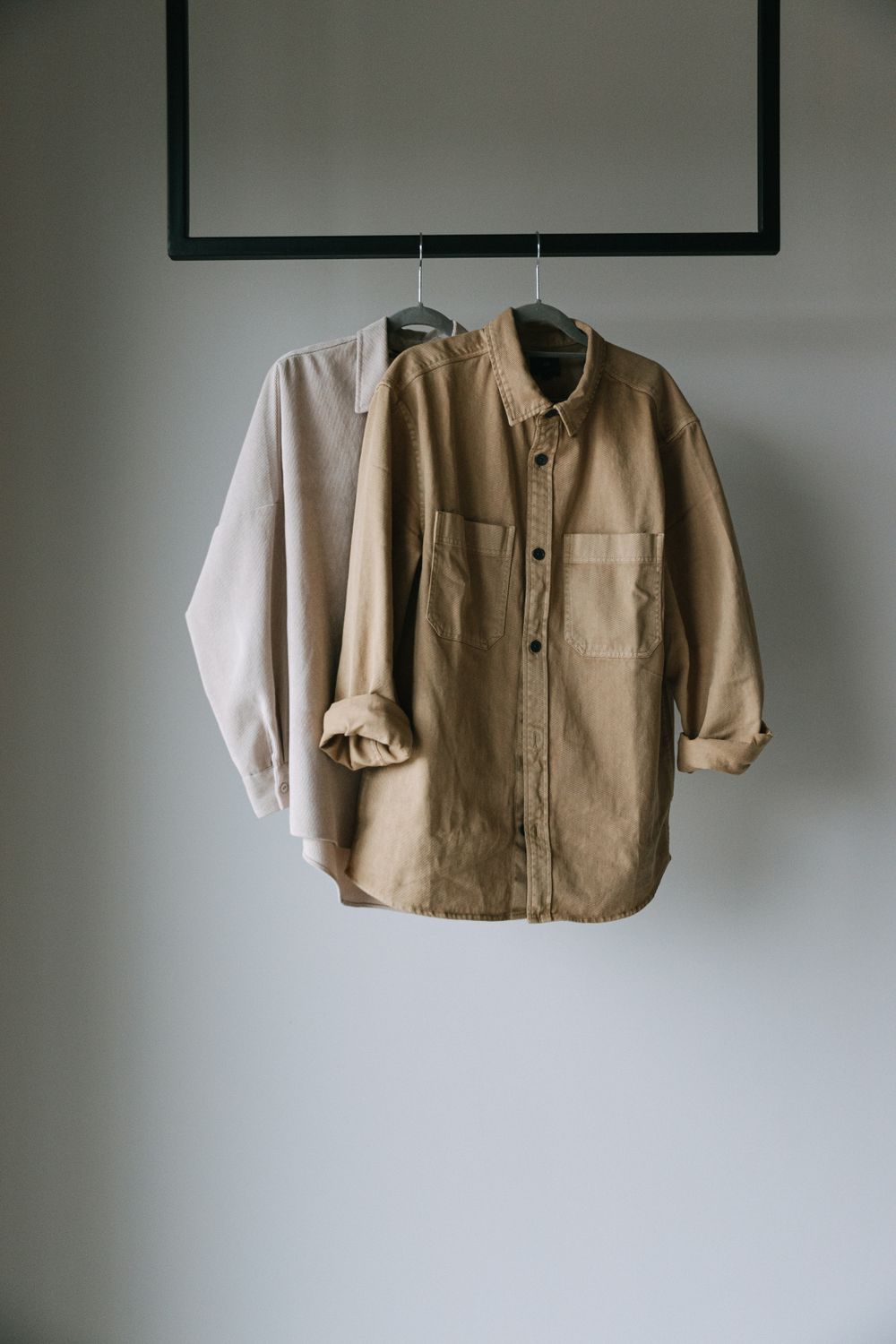 Neutral shirting hung along a rail against a pale wall