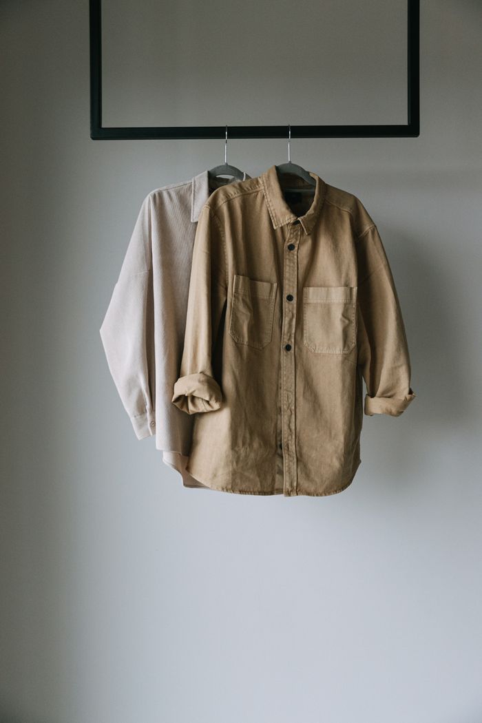 Neutral overshirts hanging on a rail, photo by Ivan S on Pexels