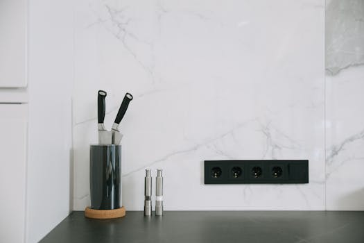 Modern kitchen with marble backsplash, knife holder, and power outlets.