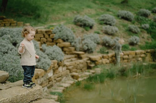 Child Standing Beside a Pond