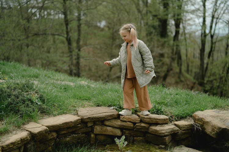 Girl In Gray Jacket And Brown Pants Walking On Brown Rocks