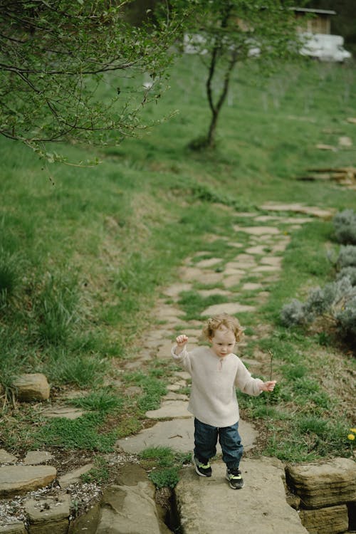 A Kid Walking on a Pathway of Rocks