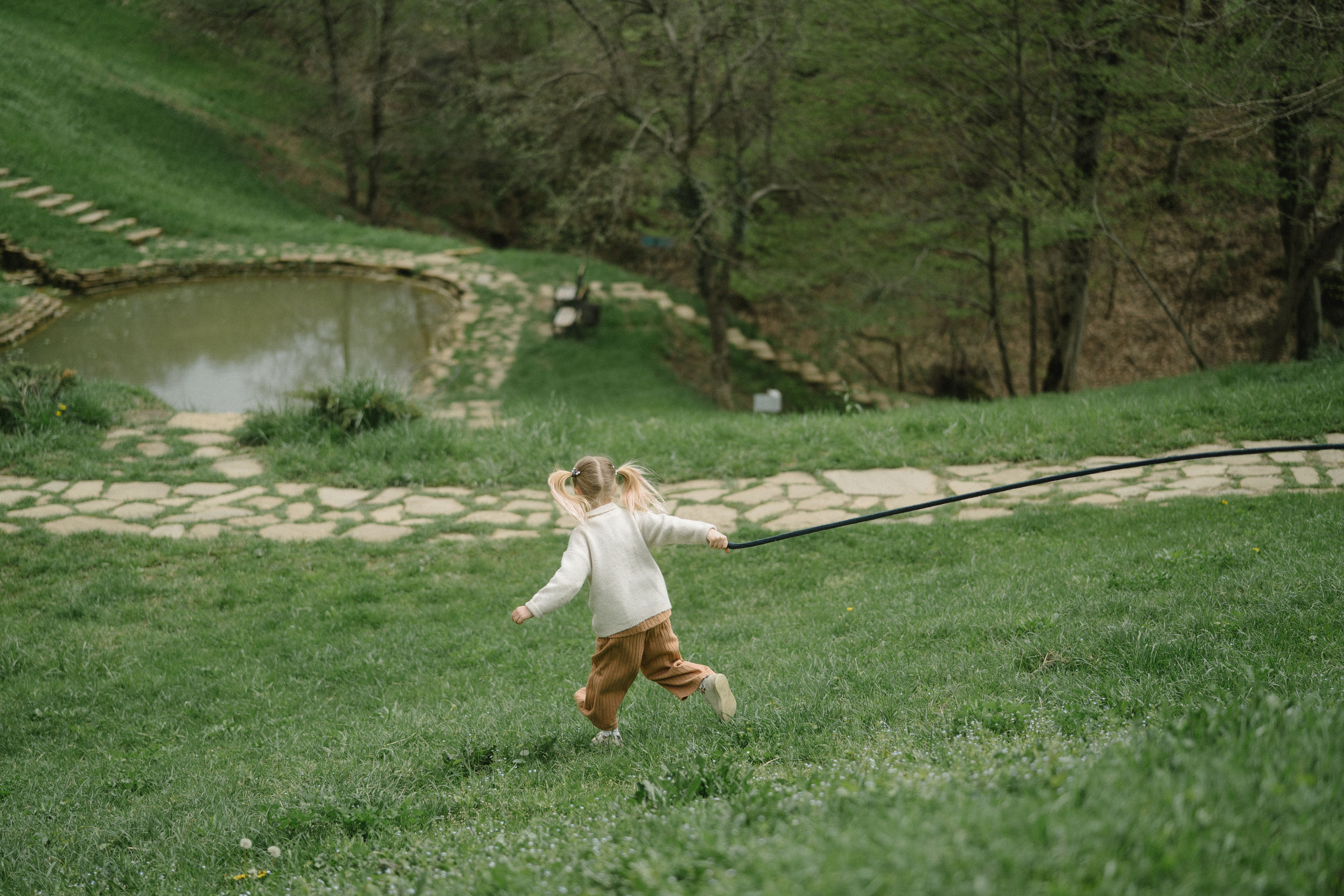 緑の芝生の公園を後ろ姿で走る子どもの写真