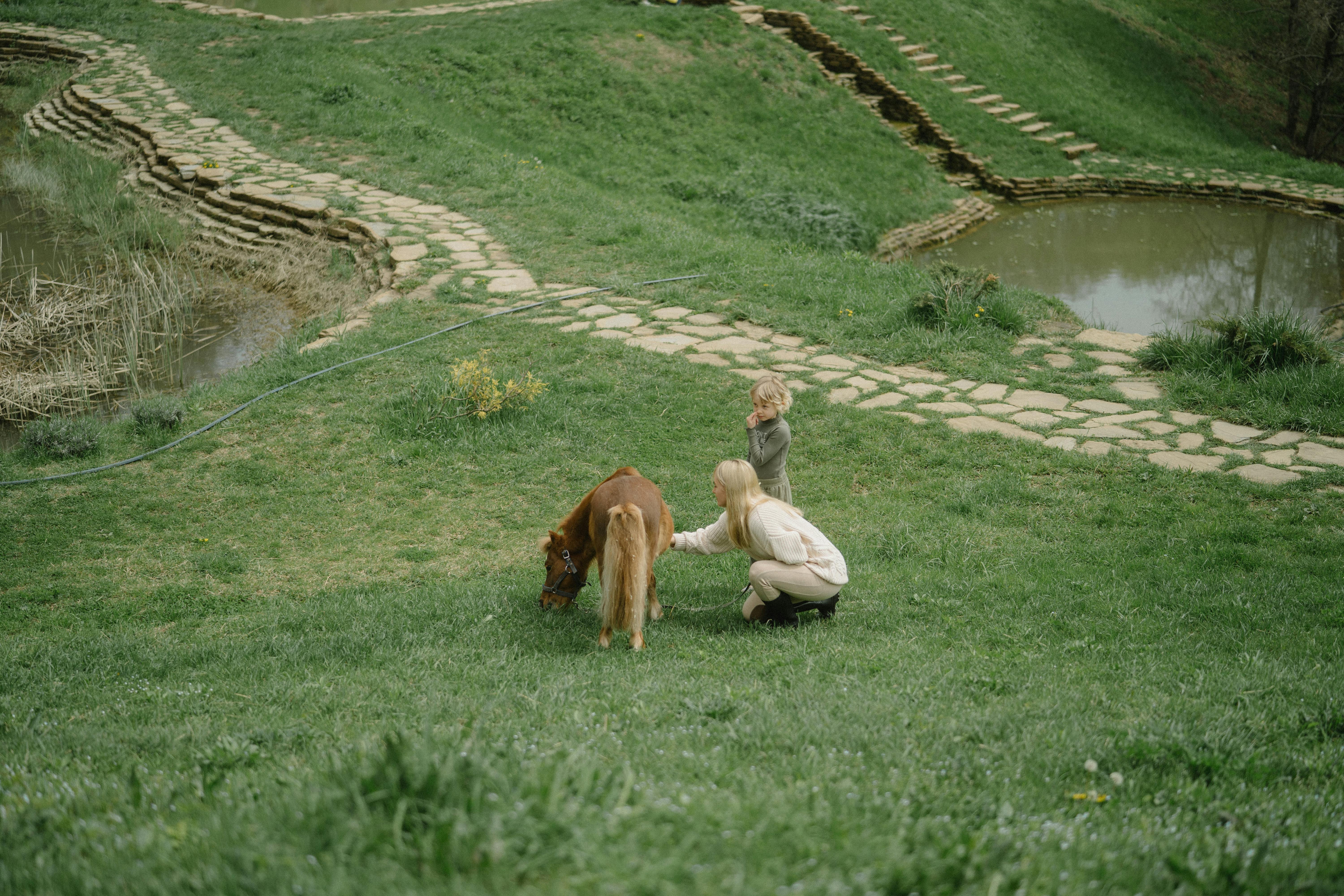 mother and child staying near a pony