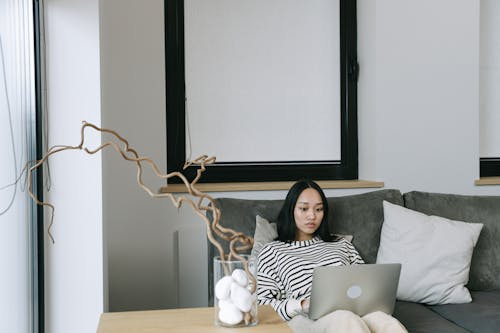 Woman Sitting on Sofa while Using a Laptop