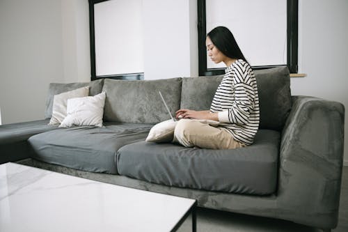 Woman Sitting on Sofa while Using a Laptop
