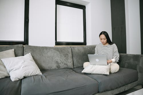 Woman Sitting on Sofa while Using a Laptop