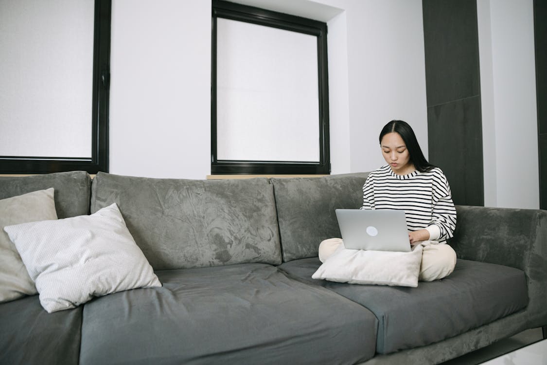 Woman Sitting on Sofa while Using a Laptop