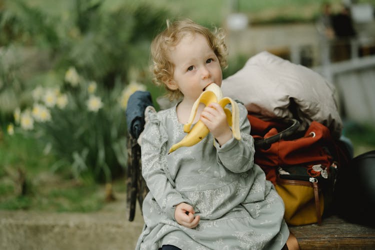 A Little Girl Eating A Banana