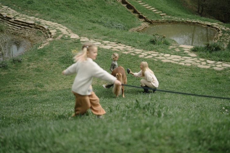 Kids Playing On Grass With Their Mother