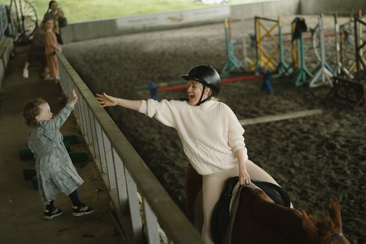 A Mother Riding A Horse Greeting Her Child