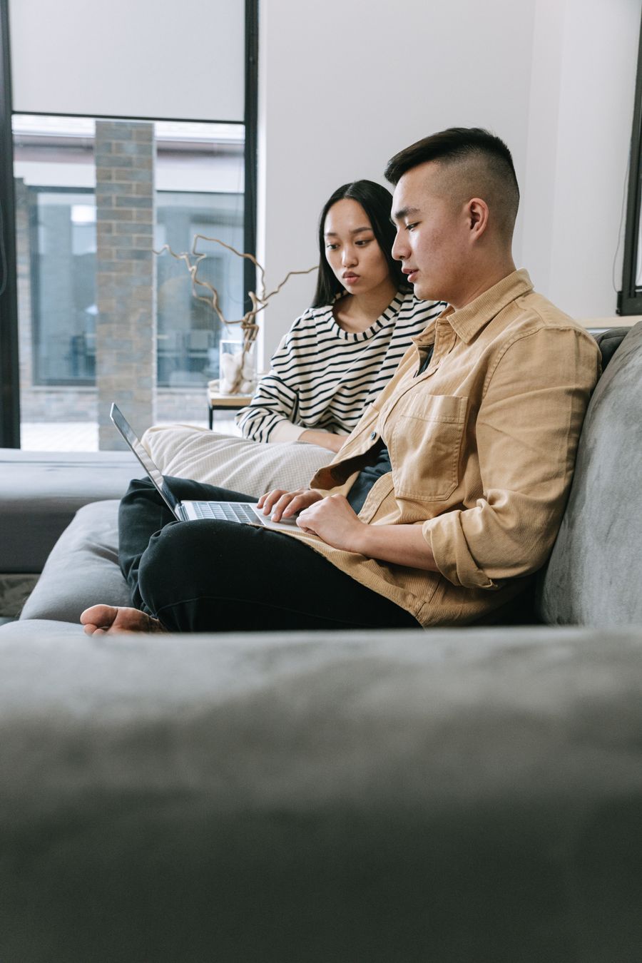 Cặp đôi ngồi trên sofa cùng xem một bài viết trên laptop