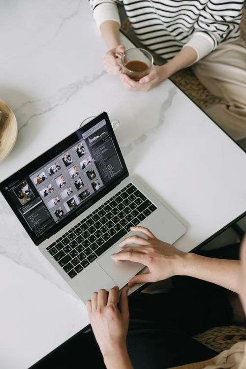Free Aerial shot of a person working on a laptop with coffee, ideal for remote work and productivity themes. Stock Photo