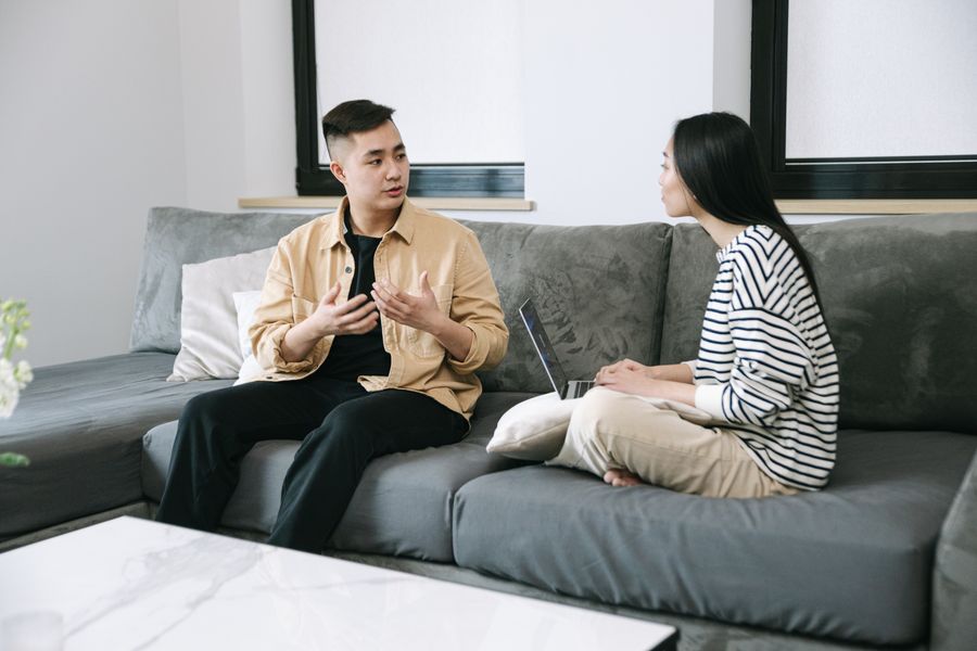Hai người ngồi trên sofa trao đổi, một người đang giải thích