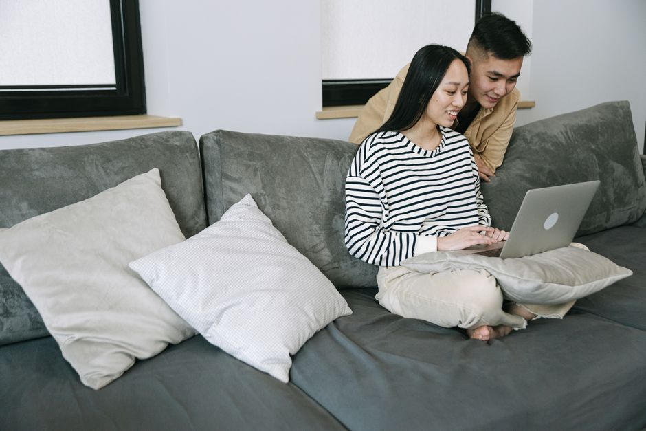 Young couple browsing on a laptop while sitting comfortably on a sofa at home.