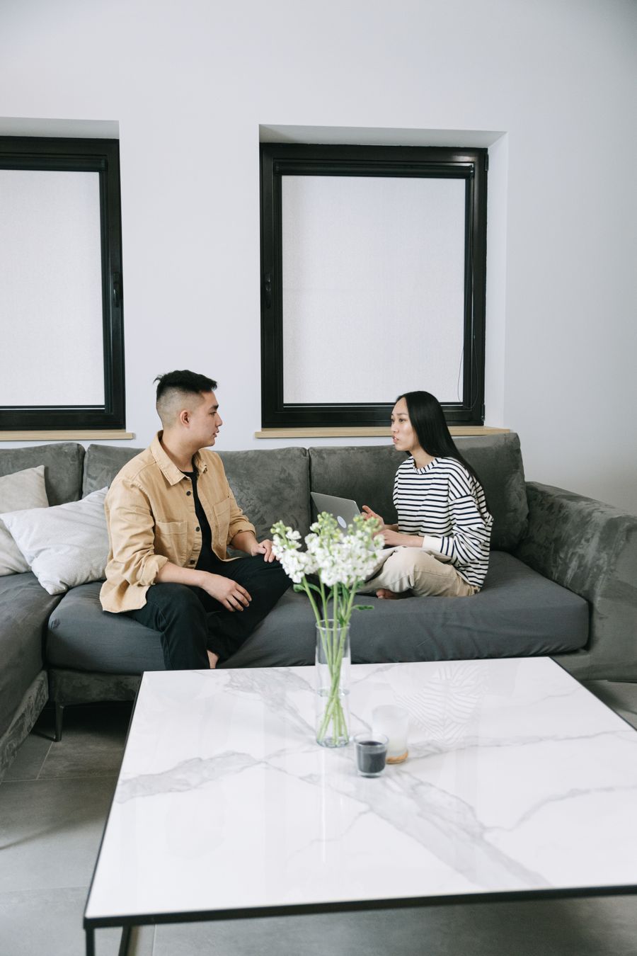 Hai người ngồi trò chuyện điềm tĩnh trên sofa phòng khách