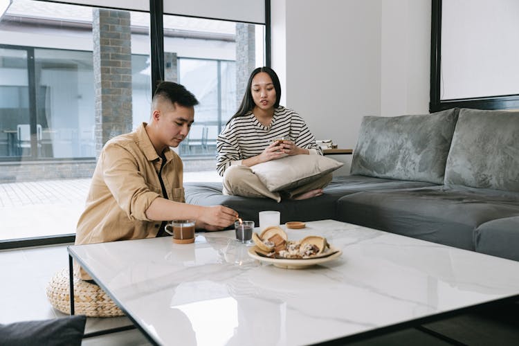 Man And Woman Sitting On The Couch Lighting A Candle