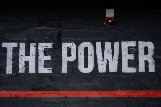 Close-up of 'The Power' graffiti on a dark wall, emphasizing strength and impact.