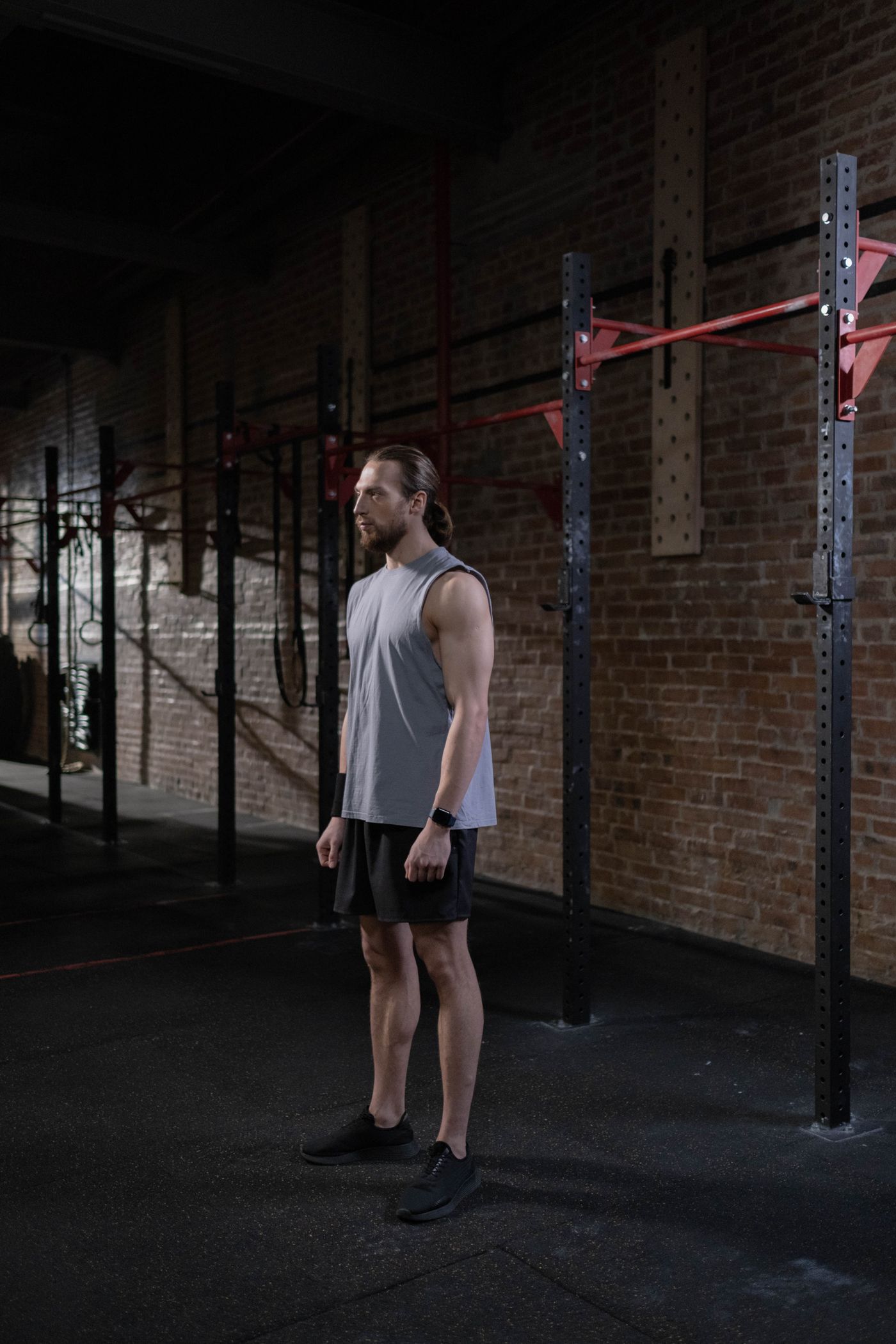 Man in a grey tank top standing in a brick-wall gym