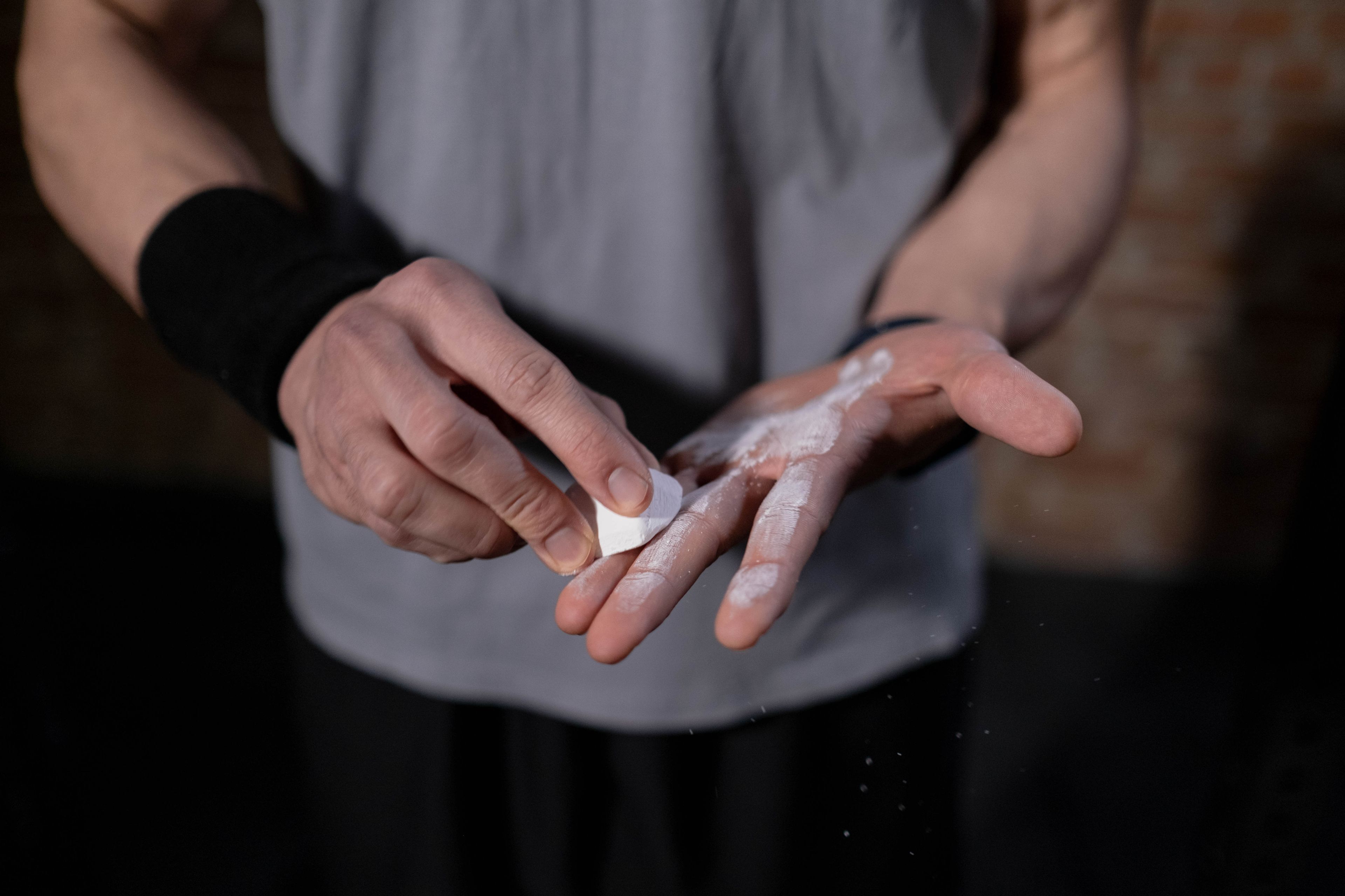 Athlete's hands applying gym chalk before exercise for improved grip.