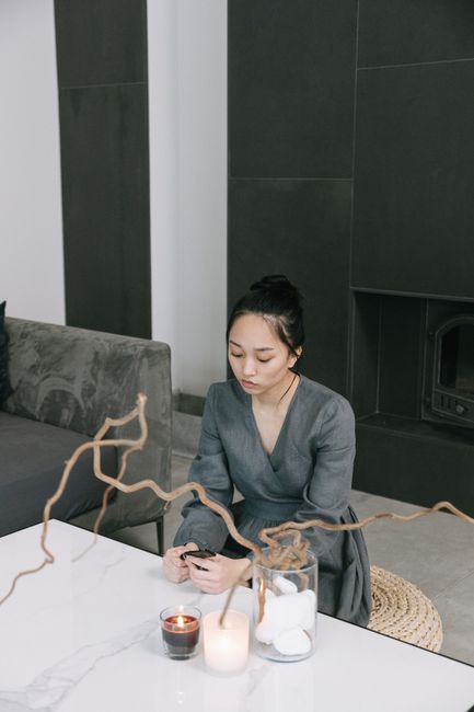 A woman in a gray dress sits quietly in a modern, minimalist living room setting.