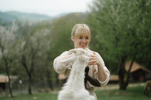 Woman in White Knitted Sweater Standing beside White Animal
