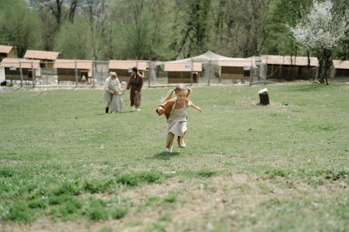 Child Wearing a Apron Running on Grass Field