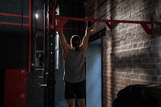 Man in activewear doing pull-ups in an indoor gym setting, emphasizing fitness and well-being.