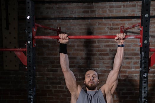 Man exercising on pull-up bar in gym, showcasing strength and fitness.