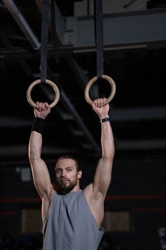 Athletic man performing exercises on gymnastic rings indoors, showcasing strength and fitness.