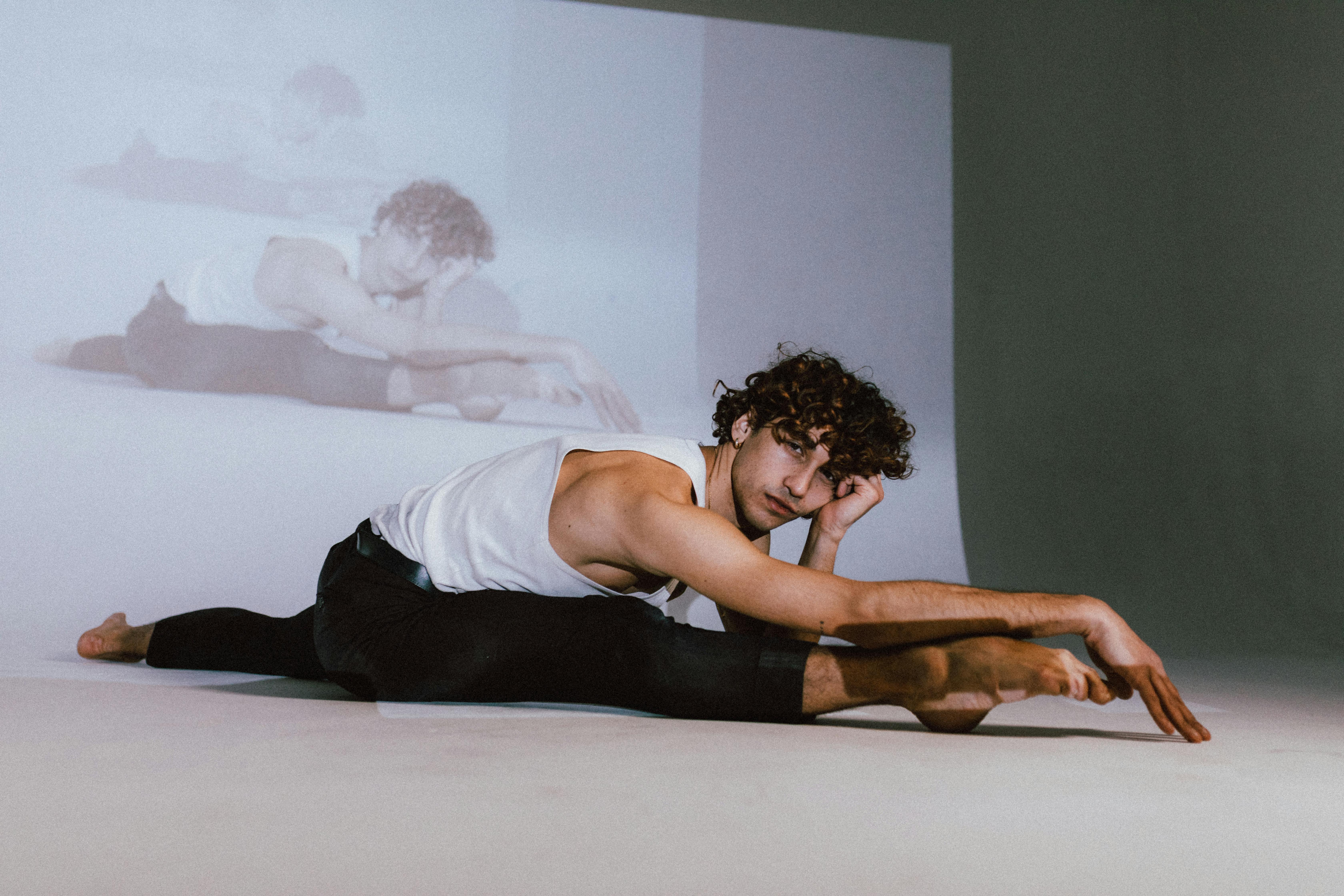 man in black tank top doing leg split