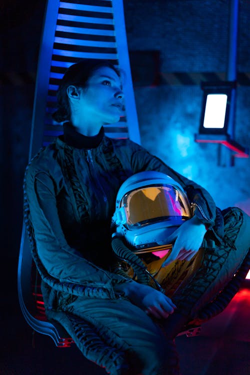 Free Woman Wearing A Spacesuit Sitting On A Metal Chair Stock Photo